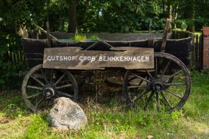 Ein alter Pferdewagen mit Schild mit Aufschrift Gutshof Groß-Behnkenhagen